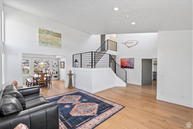 4104 S Bridlewood Dr E, Bountiful, UT 84010 - living area featuring stairs, light wood finished floors, recessed lighting, a high ceiling, and a textured ceiling