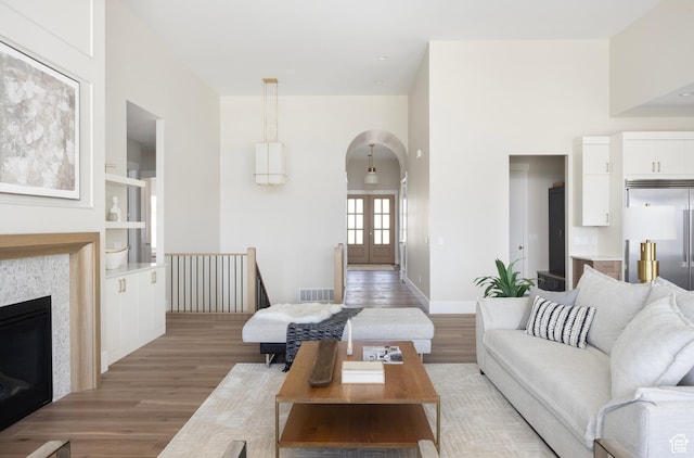 14277 S Keely Ct, Bluffdale, UT 84065 - living room with arched walkways, light wood-style flooring, built in features, and french doors