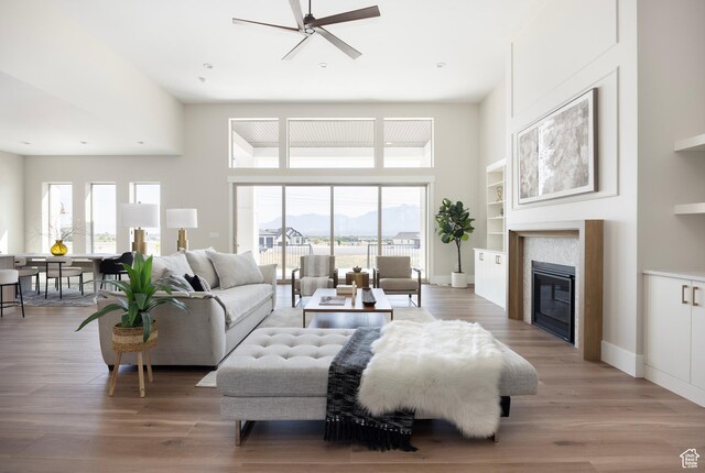 14277 S Keely Ct, Bluffdale, UT 84065 - living area with a ceiling fan, a mountain view, light wood-style floors, a tile fireplace, and a towering ceiling