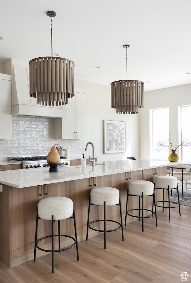 14277 S Keely Ct, Bluffdale, UT 84065 - kitchen with white cabinetry, decorative backsplash, light wood-style floors, and a kitchen bar