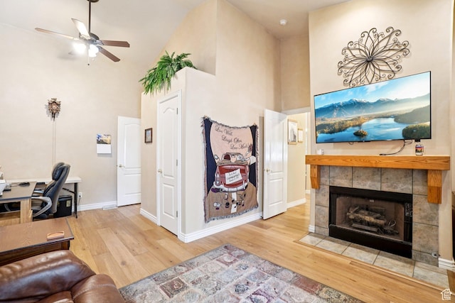 798 E Spruce Tree Ln, Sandy, UT 84094 - living room featuring wood finished floors, a high ceiling, a ceiling fan, a tile fireplace, and a desk
