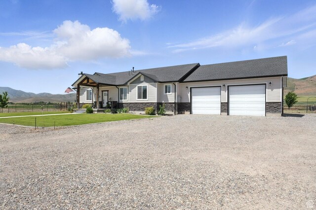968 S 5400 W, Malad City, ID 83252 - view of front facade with stone siding, driveway, an attached garage, and a mountain view