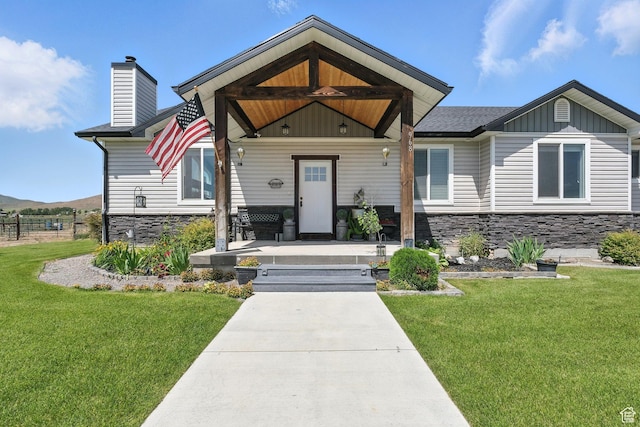 968 S 5400 W, Malad City, ID 83252 - view of front of home with stone siding, a front yard, a porch, a chimney, and board and batten siding