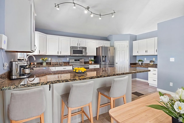 2177 N 125 W, Layton, UT 84041 - kitchen with appliances with stainless steel finishes, a peninsula, white cabinets, a breakfast bar area, and dark stone counters
