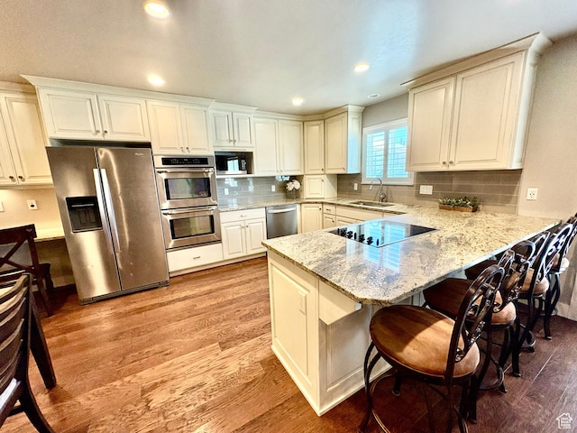 966 E 2810 S, Heber City, UT 84032 - kitchen featuring appliances with stainless steel finishes, light wood-type flooring, a peninsula, a kitchen breakfast bar, and light stone countertops