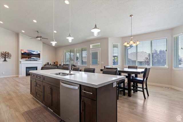 1381 W 425 S, Layton, UT 84041 - kitchen with stainless steel dishwasher, a textured ceiling, dark brown cabinetry, a glass covered fireplace, and plenty of natural light