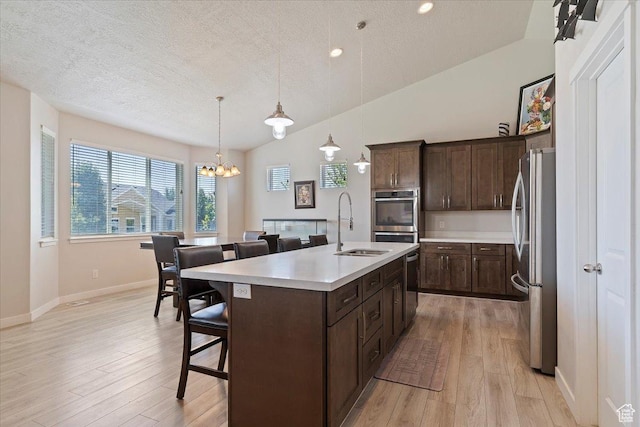 1381 W 425 S, Layton, UT 84041 - kitchen featuring appliances with stainless steel finishes, a kitchen bar, dark brown cabinetry, light countertops, and light wood-type flooring