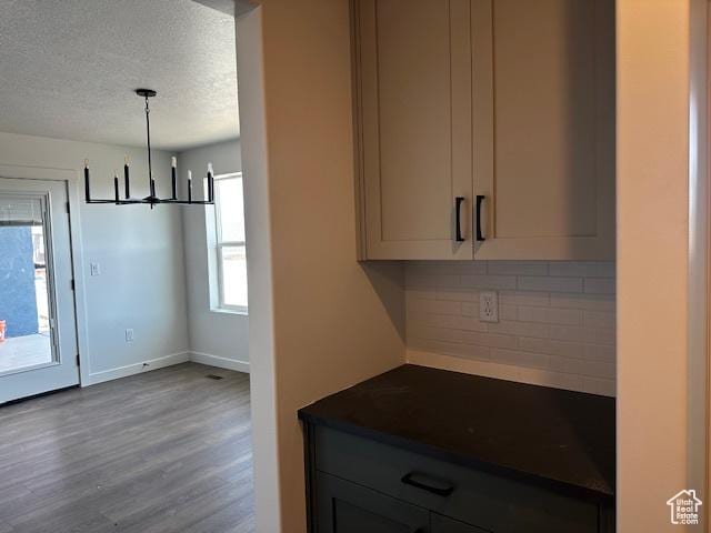 3581 W 725 S Unit 105, West Weber, UT 84401 - kitchen with dark countertops, backsplash, a chandelier, wood finished floors, and a textured ceiling