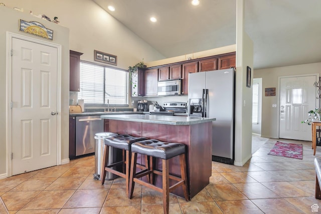 6088 W Graceland Way, West Jordan, UT 84081 - kitchen featuring stainless steel appliances, a kitchen island, recessed lighting, light tile patterned floors, and a kitchen bar
