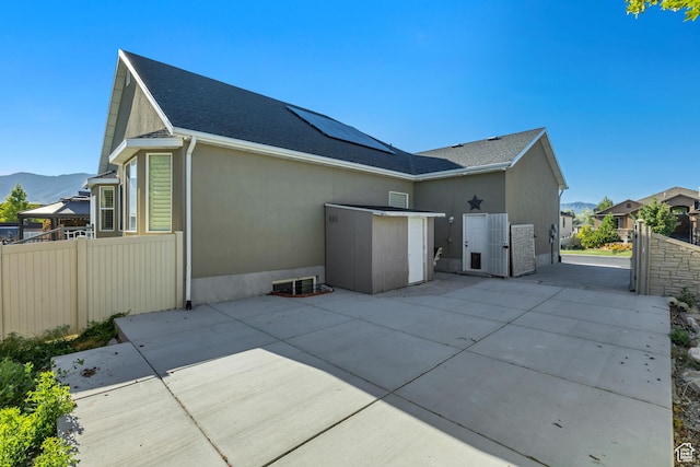 468 W Sunnyrise Ln S, Stansbury Park, UT 84074 - rear view of property featuring roof mounted solar panels, a patio, stucco siding, a mountain view, and roof with shingles
