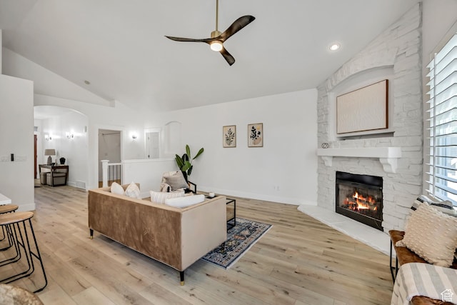 468 W Sunnyrise Ln S, Stansbury Park, UT 84074 - living room with ceiling fan, vaulted ceiling, a fireplace, arched walkways, and light wood-style flooring