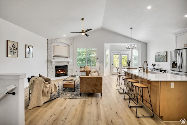 468 W Sunnyrise Ln S, Stansbury Park, UT 84074 - living area featuring vaulted ceiling, a ceiling fan, a fireplace, light wood-style flooring, and a chandelier
