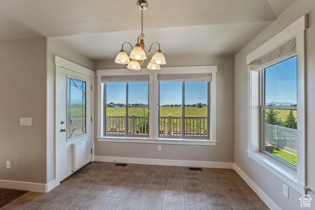 1717 N 4325 W, West Point, UT 84015 - unfurnished dining area featuring a chandelier, plenty of natural light, a textured ceiling, and wood finished floors