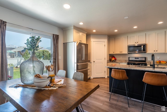 244 W 380 S Unit 10B, American Fork, UT 84003 - kitchen with appliances with stainless steel finishes, recessed lighting, wood finished floors, light stone counters, and a breakfast bar