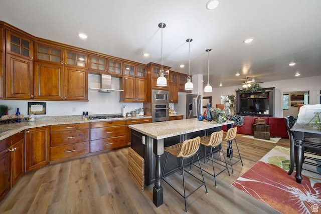 3601 S 5650 W, West Valley City, UT 84128 - kitchen featuring appliances with stainless steel finishes, wall chimney range hood, open floor plan, brown cabinetry, and a kitchen bar