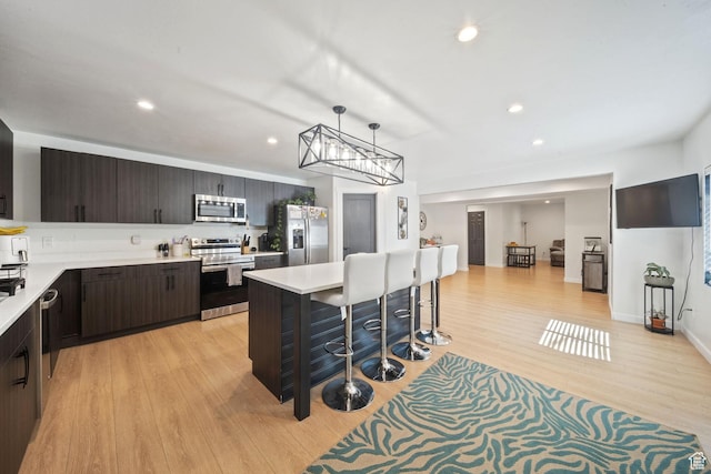 3601 S 5650 W, West Valley City, UT 84128 - kitchen with appliances with stainless steel finishes, light countertops, dark brown cabinets, a breakfast bar, and light wood-style flooring
