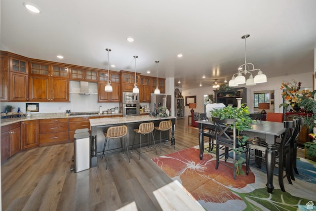 3601 S 5650 W, West Valley City, UT 84128 - kitchen with appliances with stainless steel finishes, brown cabinetry, recessed lighting, a kitchen bar, and a center island with sink