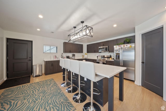 3601 S 5650 W, West Valley City, UT 84128 - kitchen with appliances with stainless steel finishes, dark brown cabinets, light countertops, light wood-type flooring, and pendant lighting