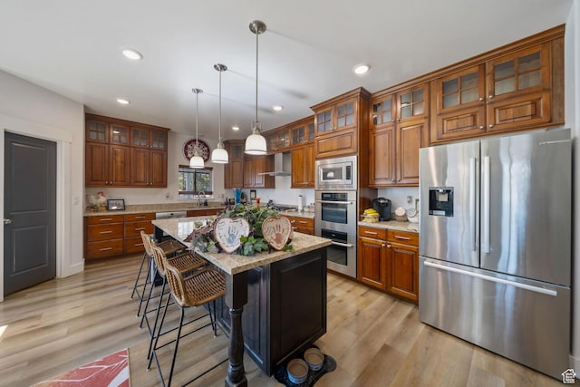 3601 S 5650 W, West Valley City, UT 84128 - kitchen featuring stainless steel appliances, brown cabinetry, recessed lighting, hanging light fixtures, and light wood finished floors