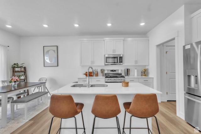 631 W 550 N, Smithfield, UT 84335 - kitchen with appliances with stainless steel finishes, light wood-type flooring, a kitchen bar, light countertops, and a center island with sink