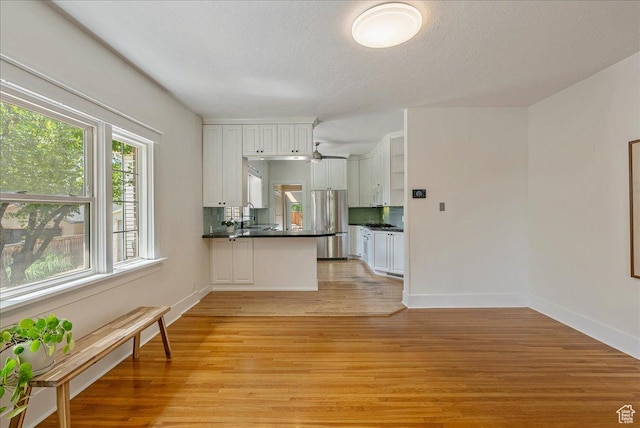 1351 E Browning Ave S, Salt Lake City, UT 84105 - kitchen with freestanding refrigerator, light wood-style flooring, dark countertops, white cabinets, and a peninsula