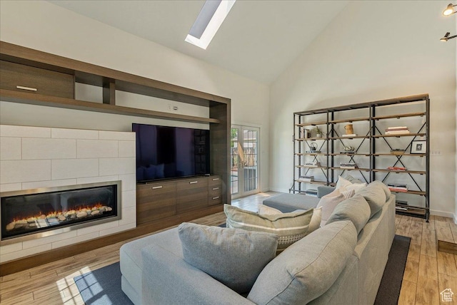 1351 E Browning Ave S, Salt Lake City, UT 84105 - living room featuring high vaulted ceiling, a tiled fireplace, light wood-type flooring, and a skylight