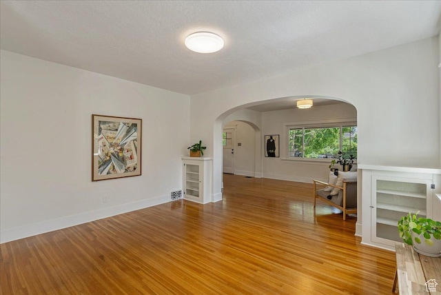 1351 E Browning Ave S, Salt Lake City, UT 84105 - unfurnished room featuring light wood finished floors, arched walkways, and a textured ceiling