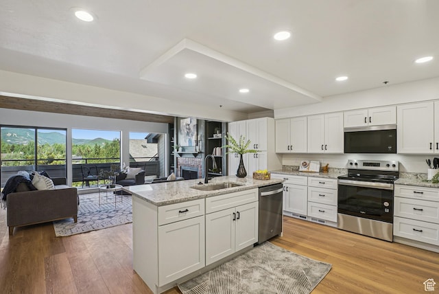2174 Fenchurch Dr, Park City, UT 84060 - kitchen featuring appliances with stainless steel finishes, open floor plan, white cabinets, light wood finished floors, and an island with sink
