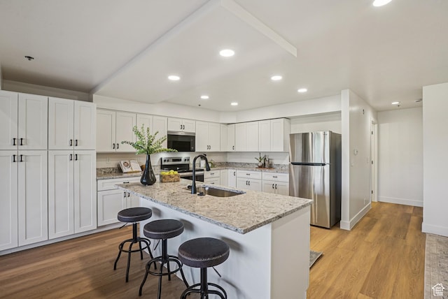 2174 Fenchurch Dr, Park City, UT 84060 - kitchen with stainless steel appliances, white cabinets, light wood-type flooring, a kitchen bar, and recessed lighting