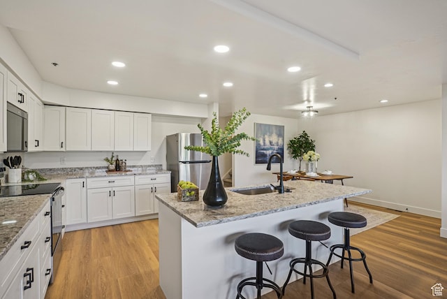2174 Fenchurch Dr, Park City, UT 84060 - kitchen with appliances with stainless steel finishes, a breakfast bar, light wood-style flooring, white cabinets, and light stone countertops
