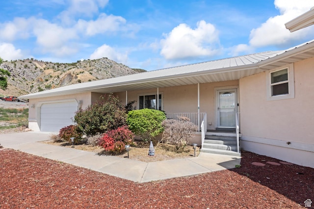 890 E Monroe Canyon Rd S, Monroe, UT 84754 - view of front of property featuring stucco siding, a porch, a mountain view, a garage, and a metal roof