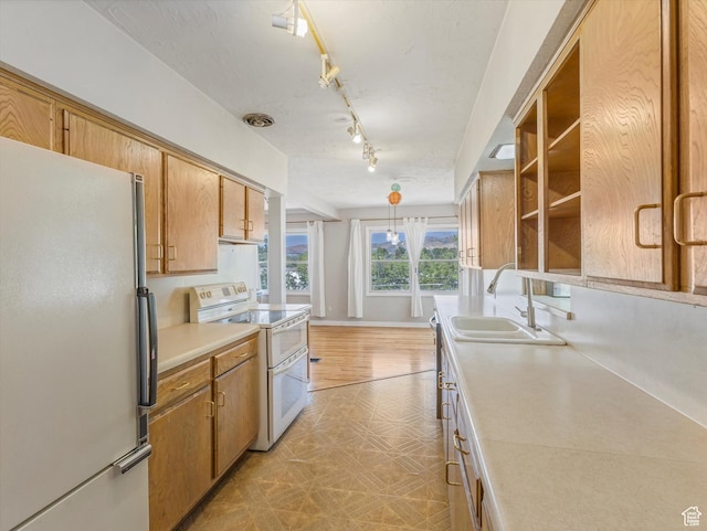 1815 E Hillcrest Ave, Salt Lake City, UT 84106 - kitchen featuring white appliances, light countertops, brown cabinetry, light floors, and rail lighting