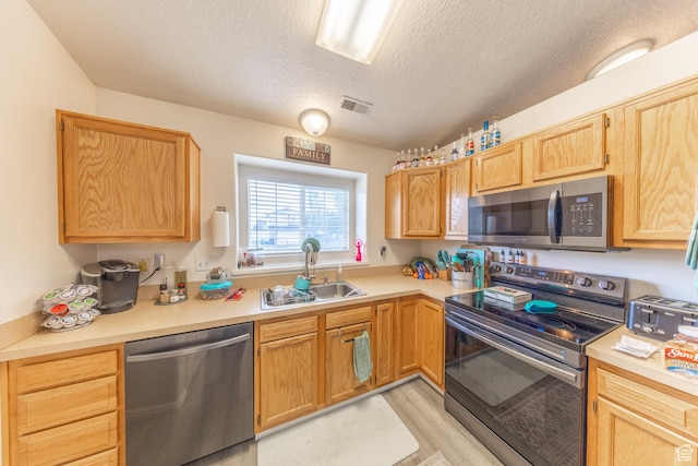 3762 W 4700 S, Roy, UT 84067 - kitchen with appliances with stainless steel finishes, a textured ceiling, light countertops, light wood-type flooring, and light brown cabinets