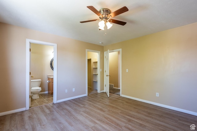 494 W 600 S, Tooele, UT 84074 - unfurnished bedroom featuring wood finished floors, a spacious closet, connected bathroom, a closet, and a ceiling fan