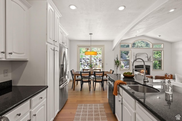 5155 S Alvera Dr E, Holladay, UT 84117 - kitchen featuring a warm lit fireplace, white cabinets, light wood-style flooring, stainless steel fridge with ice dispenser, and lofted ceiling