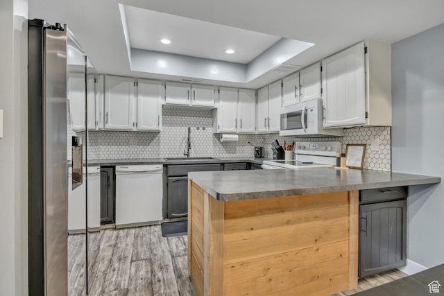 4851 S Woodbridge Dr Unit 38, Holladay, UT 84117 - kitchen with white appliances, a peninsula, light wood finished floors, a raised ceiling, and decorative backsplash