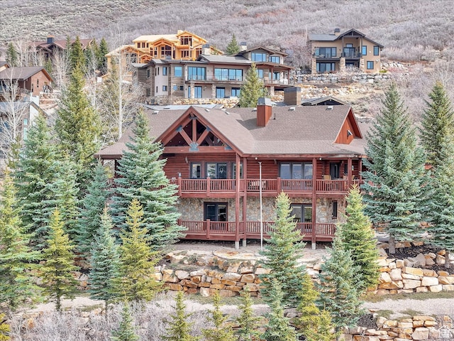 12069 N Sage Hollow Cir, Heber City, UT 84032 - rear view of house featuring a balcony, stone siding, a mountain view, and a chimney