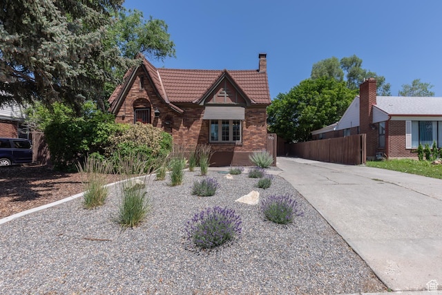 1723 E 2100 S, Salt Lake City, UT 84106 - tudor house featuring a tiled roof, driveway, a chimney, and brick siding