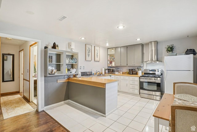 1174 Oakmont Ln, Provo, UT 84604 - kitchen with wall chimney range hood, appliances with stainless steel finishes, a peninsula, wood counters, and recessed lighting