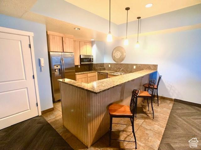 4276 S Main St W Unit 210, Murray, UT 84107 - kitchen featuring stainless steel appliances, a peninsula, a kitchen breakfast bar, light stone counters, and light brown cabinets