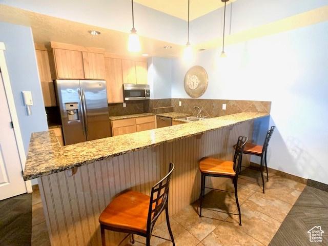 4276 S Main St W Unit 210, Murray, UT 84107 - kitchen featuring stainless steel appliances, a peninsula, light brown cabinets, a breakfast bar, and light stone countertops