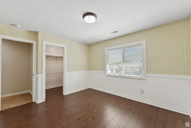 14318 S Butterfield Park Way, Herriman, UT 84096 - unfurnished bedroom with wallpapered walls, wainscoting, dark wood finished floors, a walk in closet, and a closet