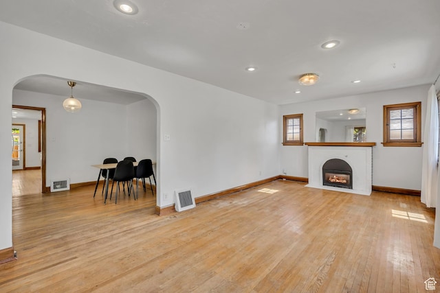 1252 E Bryan Ave S, Salt Lake City, UT 84105 - unfurnished living room with arched walkways, light wood-style floors, healthy amount of natural light, recessed lighting, and a fireplace with flush hearth