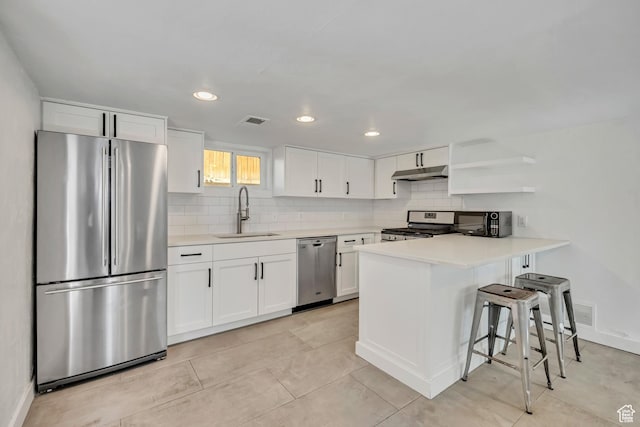 1252 E Bryan Ave S, Salt Lake City, UT 84105 - kitchen with appliances with stainless steel finishes, under cabinet range hood, decorative backsplash, white cabinets, and recessed lighting