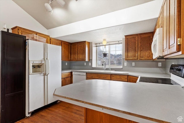 2826 W 4275 S, Roy, UT 84067 - kitchen with white appliances, a peninsula, brown cabinetry, vaulted ceiling, and wood finished floors