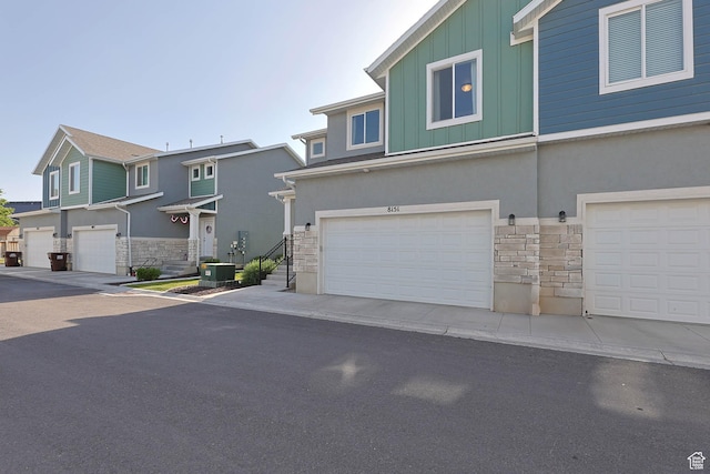 8151 St Cecilia St S, Eagle Mountain, UT 84005 - view of front of home featuring stone siding, board and batten siding, a garage, and stucco siding