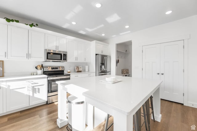 8151 St Cecilia St S, Eagle Mountain, UT 84005 - kitchen featuring stainless steel appliances, white cabinetry, light countertops, a center island, and light wood finished floors