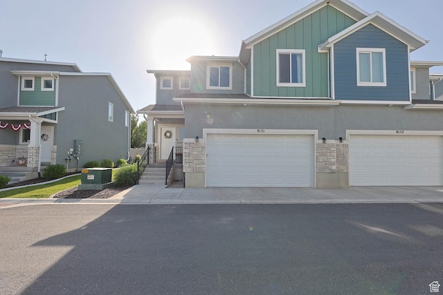 8151 St Cecilia St S, Eagle Mountain, UT 84005 - view of front facade featuring stone siding, board and batten siding, a garage, and stucco siding