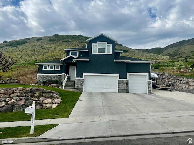6057 W Herriman View Way, Herriman, UT 84096 - view of front of house featuring stone siding, a mountain view, driveway, an attached garage, and stucco siding
