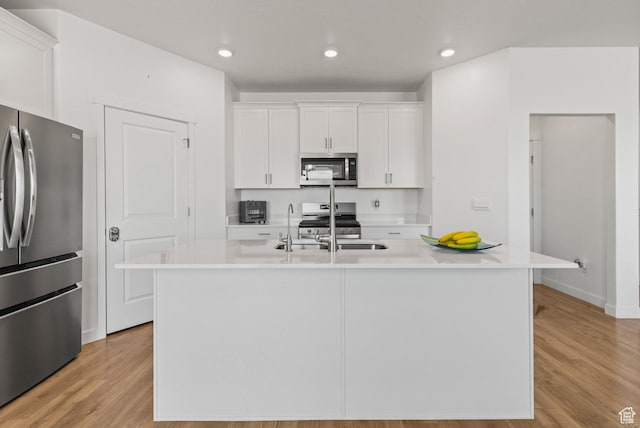 1268 S Raintree Ln, Santaquin, UT 84655 - kitchen featuring stainless steel appliances, white cabinetry, light wood-style flooring, light countertops, and a center island with sink